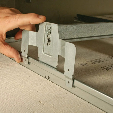 Heavy Duty Grid Brace Ceiling Box Kit With Four Inch Round Box And Two And One Eighth Inch Depth, Concentric Knockouts In One Half Inch And Three Quarter Inch, Sliding Bracket Mount, Mount Anywhere On The Bracket For Twenty Four Inch Spans, showing hand adjusting mount on ceiling grid.