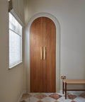 Wooden door with sleek champagne bronze cabinet pulls with escutcheon backplate, 12-5/8 inch center, in a mid-century modern hallway.