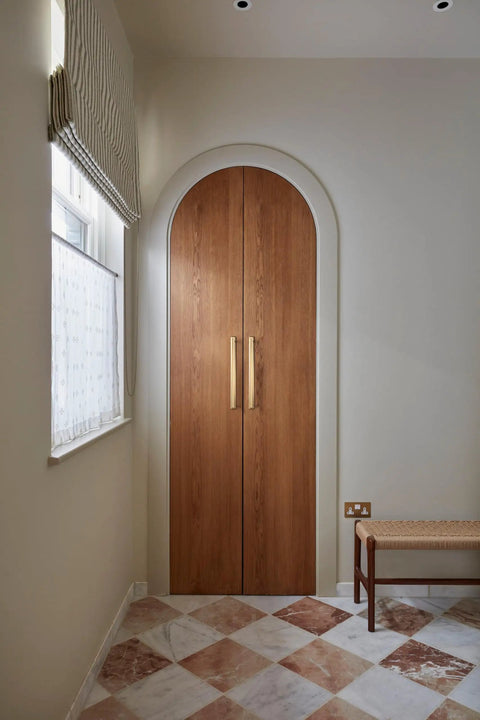 Wooden door with sleek champagne bronze cabinet pulls with escutcheon backplate, 12-5/8 inch center, in a mid-century modern hallway.