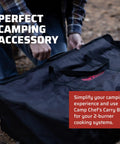 Person carrying a Carry Bag For Two Burner Stoves Heavy Duty Case With Weather Resistant Liner and EZ Glide Zippers outdoors.