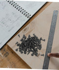 100 Piece Mini Machine Screws For Furniture Repair And DIY Projects Rock Solid Tiny Fasteners scattered on wood with a ruler.