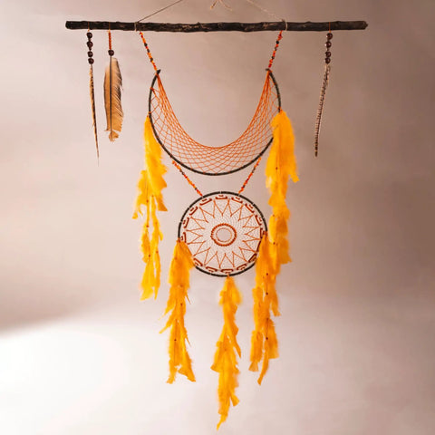 Dream catcher with yellow feathers hanging on a wood stick, featuring circular metal hoop frames and rustic decorations.