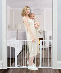 Woman holding baby beside Auto Close Safety Baby Gate For Stairs And Doorways, Extra Tall And Wide, Walk Through Design, White