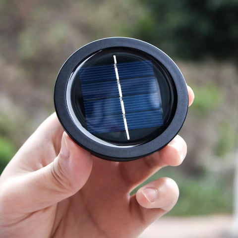 Hand holding a Four Pack Solar Light Replacement Top For Outdoor Lanterns, Waterproof And All Weather, 2.76 Inch Lid, black finish.