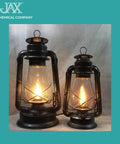 Two black JAX metal oil lanterns with glass chimneys, lit.