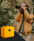 Yellow Waterproof PVC1 Hard Camera Case With Padded Dividers For Cameras Lenses And Dual Drones next to photographer outdoors