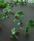 Close-up of faux clover leaf garland with green beads and small LED lights on a dark background.