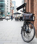 Gravel bike parked on street with front carrier rack holding a bag, showcasing aluminum alloy construction for bikepacking adventures.