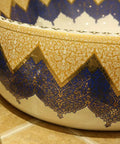 Close-up of Knockout Round Ceramic Vessel Sink With A Dope Sprayed Enamel Finish featuring intricate blue and gold design.