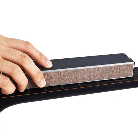 Person using 10 Inch Professional Guitar Fret Leveling Beam And Heavy Grit Sanding File Block on guitar fretboard for smoothing edges.
