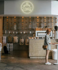 Coffee Cup Neon Sign USB Powered LED Light With 3D Engraved Art for cafe wall decor, glowing above a customer at a coffee bar.