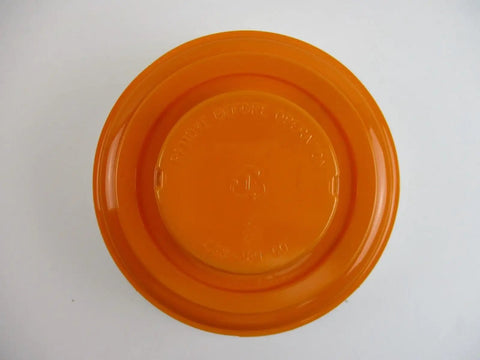 Top view of an orange round container lid, featuring embossed text and a central circular design.