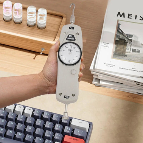 100Lb Push Pull Force Gauge Handheld Tester For Measuring Push And Pull Forces With High Accuracy Within Five Tenths Of A Percent And Lightweight Portable Design held over a keyboard