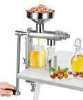 Manual Oil Press Machine For Home Use, Seed And Nut Oil Expeller For Peanut Oil, Physical Pressing Technology, shown on table with oil jar