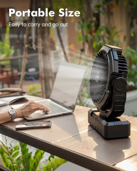 3 In 1 Camping Fan With 36000mAh Battery on table next to open laptop and smartphone, illustrating portability for outdoor use.