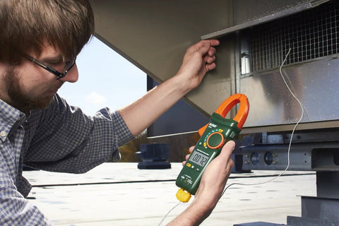Person using 400A True RMS AC Clamp Meter With Non Contact Voltage Detection to measure current in HVAC system outdoors