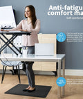 Person standing on Anti Fatigue Floor Mat Half Inch Cushioned For Kitchen And Standing Desk Non Slip Cushion With ComfortGrip Ideal For Home Office Or Garage Floor 17.3 By 28 Inches Black while working at a desk.