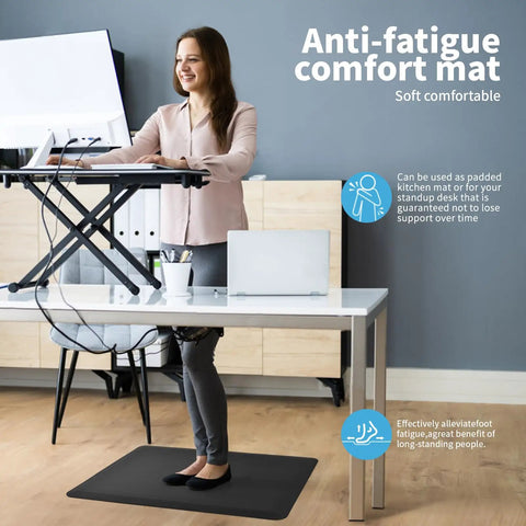 Person standing on Anti Fatigue Floor Mat Half Inch Cushioned For Kitchen And Standing Desk Non Slip Cushion With ComfortGrip Ideal For Home Office Or Garage Floor 17.3 By 28 Inches Black while working at a desk.