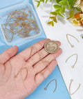 Golden V Shape Stainless Steel Earring Hooks, 50 Pcs Metal Ear Wires with Horizontal Loop shown in hand for scale.