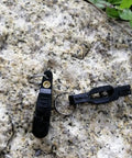 Front view of two black Keproving fishing line clips with O-shaped rings on a rock surface