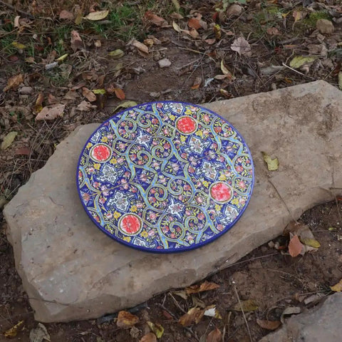 Colorful decorative ceramic plate with intricate patterns resting on a rock outdoors, not 18 Inch Wooden Lazy Susan Turntable Rotating Centerpiece For Dining Table And Kitchen Counter Must Have Solid Hardwood Storage Tray For Pantry Cupboard Organization Of Spices Dishes And Condiments Versatile Home Decor.
