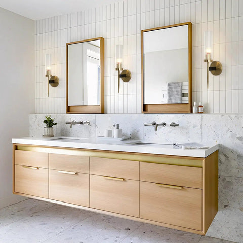 Mid Century Modern Gold Wall Light With Cylinder Glass Shade Brushed Brass Finish Long Wall Sconce For Vintage Bathroom And Hallway Mount Lamp With Lit Glow And Classic Vibe in modern bathroom setting.