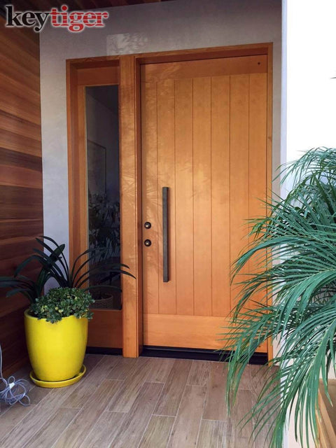Front view of 24 Inch Back To Back Modern Stainless Steel Door Handle Set in Matte Black Finish on wooden exterior door