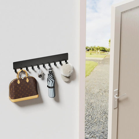 Wall Mounted Key Holder With 10 Hooks No Drill Self Adhesive Matte Black Metal Key Rack for Hallway Home Office Easy Install Keeps Keys Handy In One Spot installed on wall holding bag, keys, umbrella, and hat next to doorway.