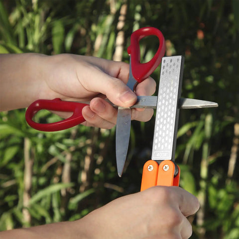 Person using Folding Pocket Diamond Sharpener For Garden Tools And Knives, Dual Sided 400 600 Grit Stone For Scissors outdoors
