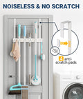 Over The Door Broom And Mop Holder With 4 Slots And 4 Hooks Rustic Wood Door Mount Organizer installed on a grey door next to a washer.