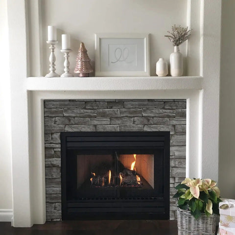 Fireplace with gray stone design on front, candles, and decor pieces on mantel
