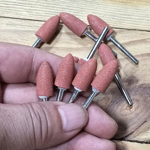 Hand holding Bullet Shape Abrasive Mounted Stone Grinding Bits Pack 18 Pcs For Rotary Tools Pro Grade Durable Red Corundum.