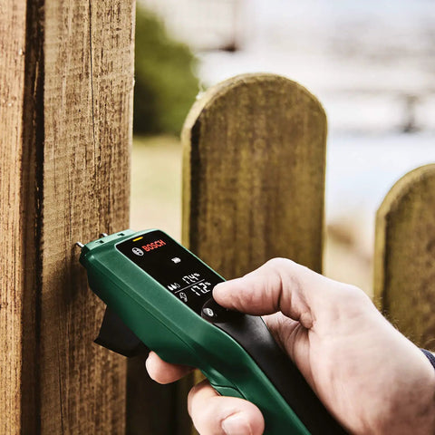Person using Wood Moisture Meter With Pin Probes, Fast Reading For DIYers And Pros to check moisture in wooden fence outdoors.