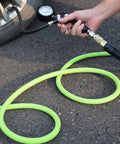 Person using Hybrid Air Hose 1/4 Inch By 50 Feet, 300 PSI Heavy-Duty, Lightweight And Kink-Resistant, inflating tire on pavement