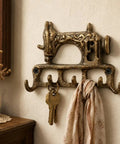 Slick Vintage Cast Iron Sewing Machine Wall Hook Rock Solid For Hanging Coats And Everyday Keys with keys and a scarf.