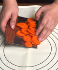 Hands using Heavy Duty Bench Scraper For Flat Top Griddle to cut carrots, showcasing stainless steel chopper with precision beveled edge.