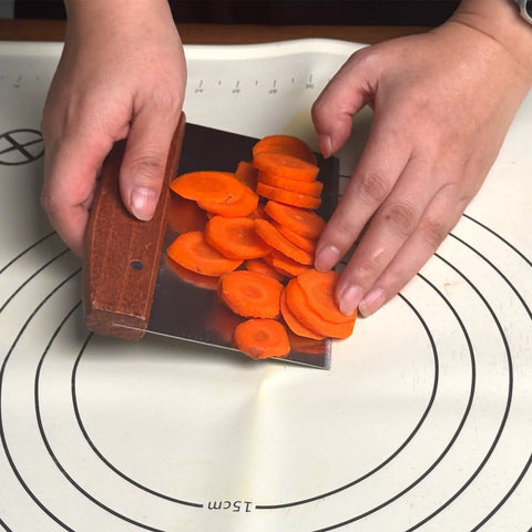 Hands using Heavy Duty Bench Scraper For Flat Top Griddle to cut carrots, showcasing stainless steel chopper with precision beveled edge.