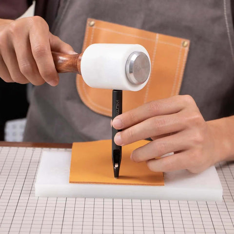 Person using Oval Leather Hole Punch Tool for Belts and Watch Straps on leather with mallet, showing hands-on crafting process