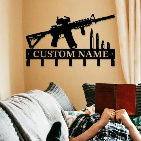 Custom Name Gun Themed Wall Hooks For Keys And Coats mounted above a person reading on a sofa, metal design.