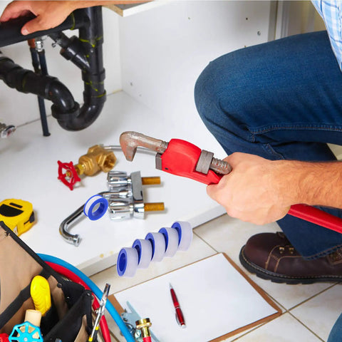 Plumber using wrench near PTFE Pipe Sealant Tape 5.5 Mil Thick Waterproof Thread Sealant For Plumbing Fittings White Handles Extreme Temps From Minus 212 To 500 Degree Fahrenheit Half Inch By 520 Inch Roll