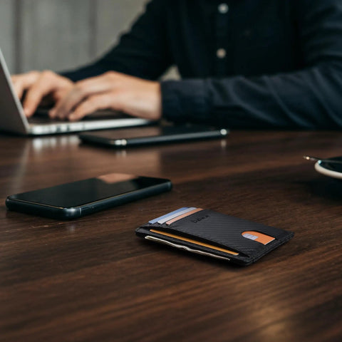 Ultra Slim Front Pocket RFID Blocking Leather Wallet For Men And Women In Carbon Fiber Black on wooden desk with cards visible