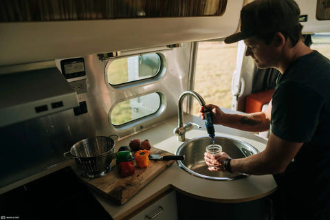 Person using Tap Water Filtration System With 0.1 Micron Inline Filter, Fits Faucets And Hose Bibs, Keeps Camp Water Fresh