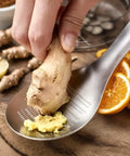 Hand using Ginger Grater Spoon And Lime Zester With Garlic Press And Wasabi Grinder, stainless steel gadget, grating ginger
