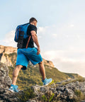 Hiker with Foldable 36W USB Solar Panel Charger With IP57 Waterproof Outdoor Power Bank on backpack in rocky landscape