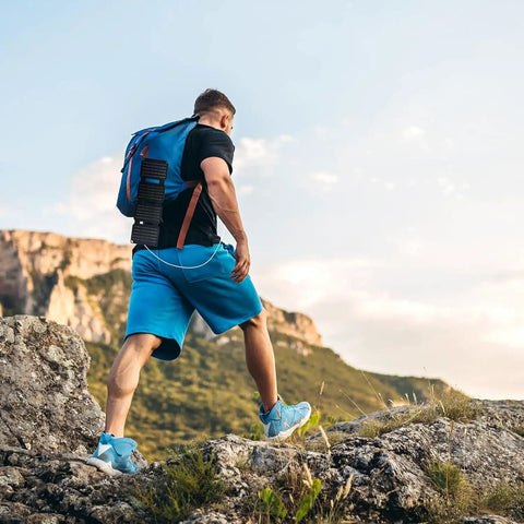 Hiker with Foldable 36W USB Solar Panel Charger With IP57 Waterproof Outdoor Power Bank on backpack in rocky landscape