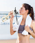 Woman drinking from 32 Oz Tritan Sports Water Bottle For Gym, Running, Hiking And Travel, BPA Free, Leakproof, at the beach