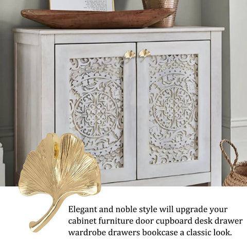 Six Piece Ginkgo Leaf Cabinet Knobs And Solid Zinc Drawer Pulls In Rustproof Brushed Gold Finish on a white cupboard with intricate design.