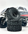 Black Label M/T 63mm by 21mm RC Tires for 1/24 Crawlers stacked near a micro crawler in a rock crawling setup