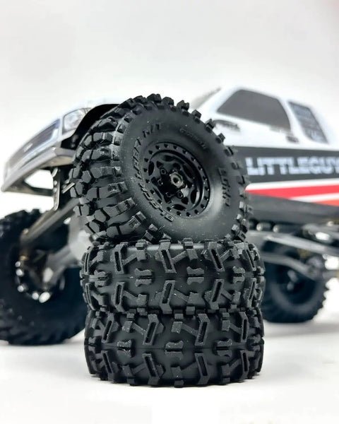 Black Label M/T 63mm by 21mm RC Tires for 1/24 Crawlers stacked near a micro crawler in a rock crawling setup