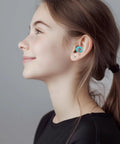 Smiling person wearing Ultra Comfortable Noise Canceling Earplugs For Sleep And Focus, Flexible Reusable Two Pack, Light Green.
